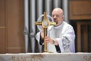 Priest places the monstrance on the altar at St. Christine Parish