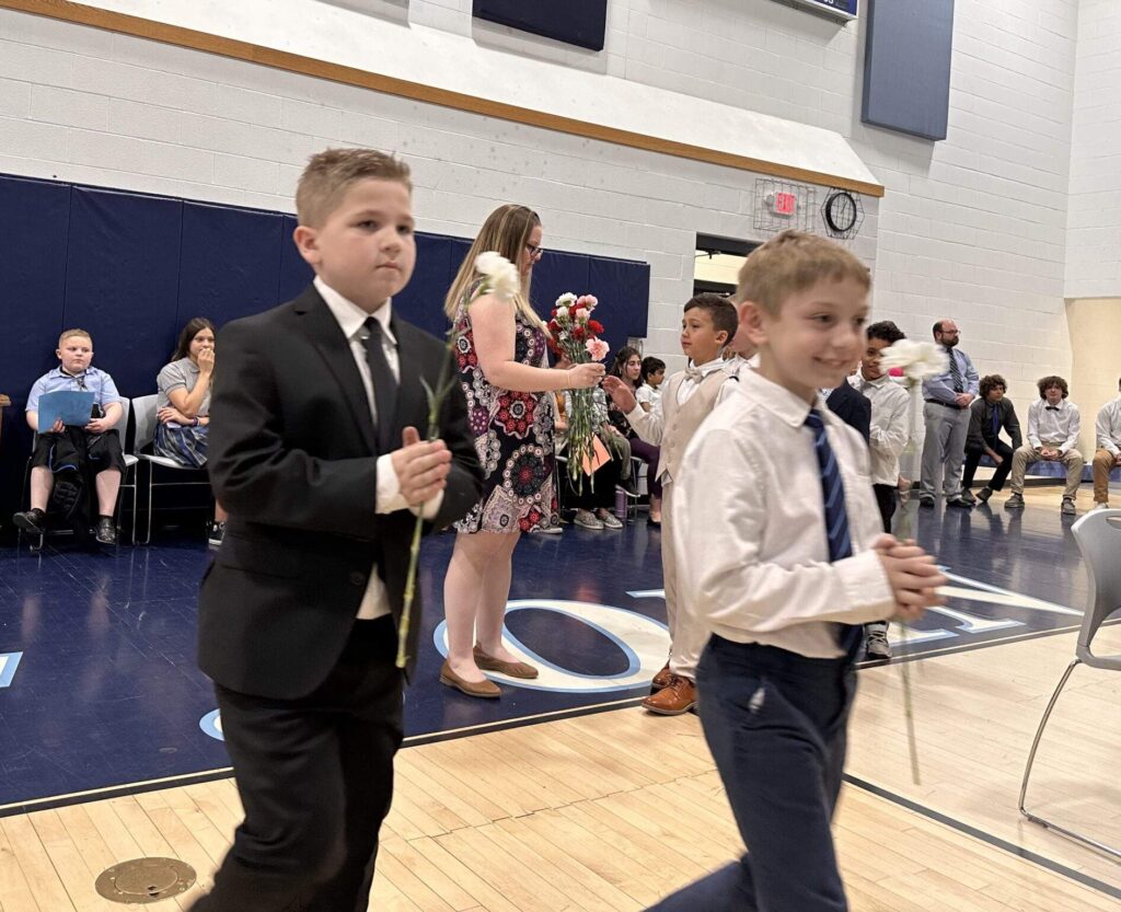 Two second grade boys process with flowers for the May crowning.