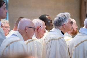 Priests stand during Mass