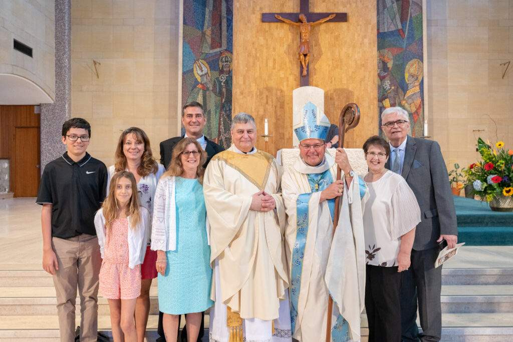 Father England stands with his family