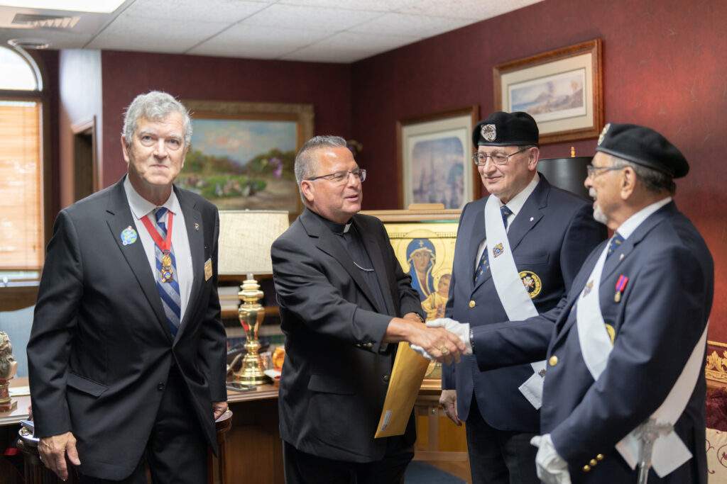 Bishop shakes hand of Knight of Columbus