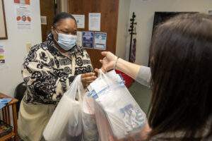 Woman hands shopping bags full of groceries to a mother.