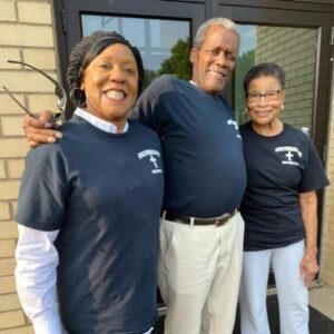 Three volunteers pose outside the church on a dinner day