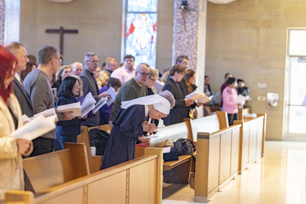 A religious sister bows down in prayer during the Rite of Election in 2024. Photo by Brian Keith.