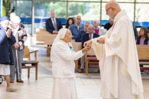 75-year Jubilarian receives communion at her jubilee Mass. Photo by Brian Keith.