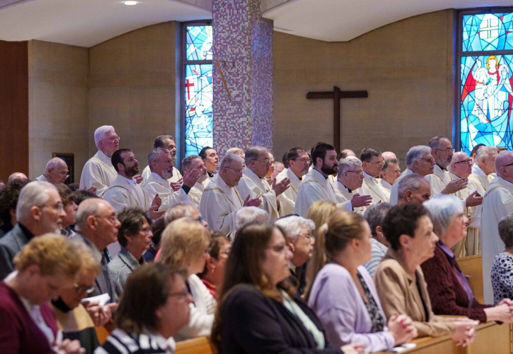 Priests stand and offer a blessing with the Bishop. Photo by Jimmy Joe Savage. Chrism Mass 2024.