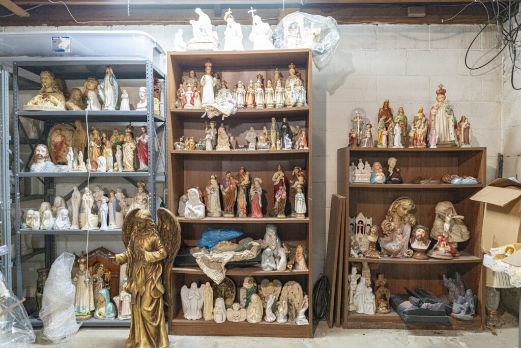 Image of Michael Irwin's workshop, featuring several bookshelves overflowing with statues. Photo by Brian Keith.