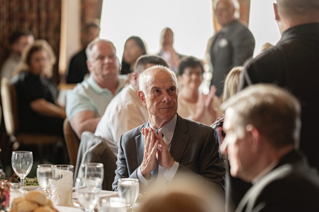 Man claps, seated in the crowd at the Golden Apple Awards 2024.