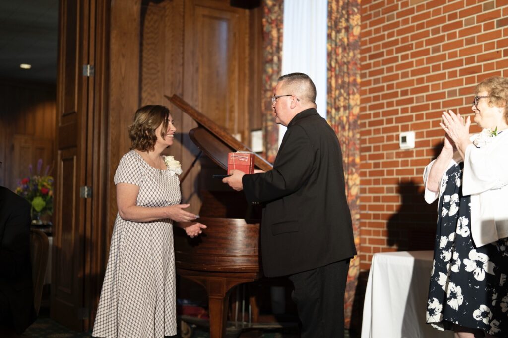 Bishop gives golden apple award to woman in checkered dress