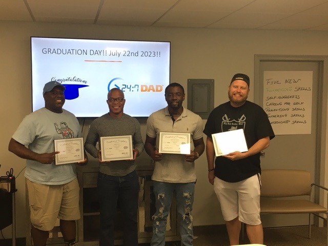 Image of four men holding certificates after completion of the Mercy Health Program