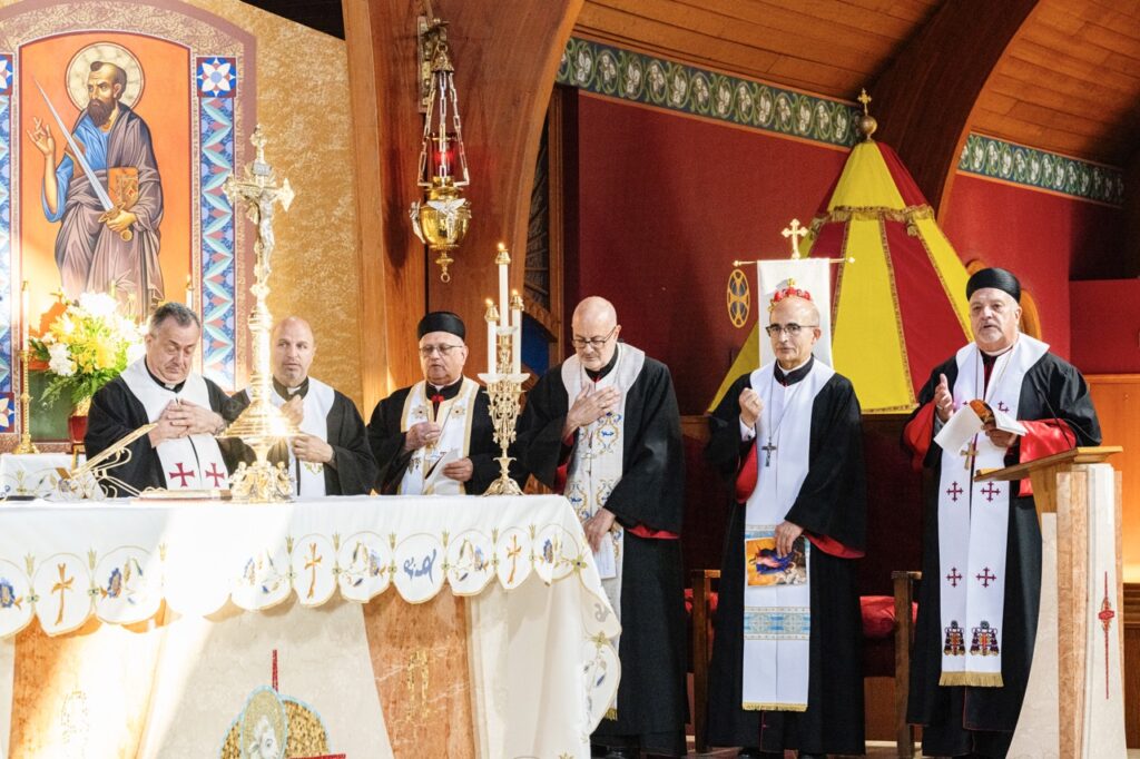 Eastern rite priests bow their heads in prayer behind the altar for the Assumption Pilgrimage in North Jackson. Photo by Brian Keith.