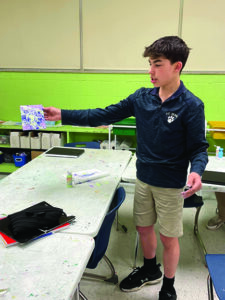 Student shows off his work from Fine Art class