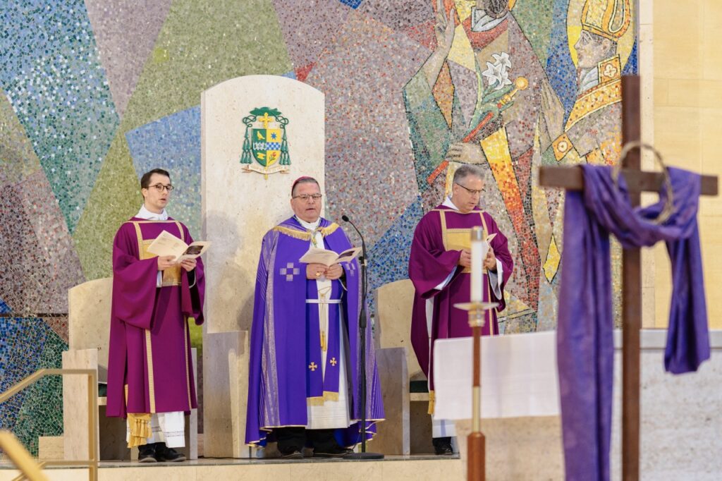 Bishop Bonnar stands, flanked by a priest and a deacon during the Rite of Election. Photo by Brian Keith.