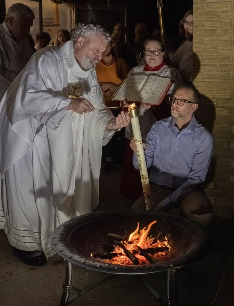 Father lights the Easter candle from the Easter flame at St. Ann Parish.