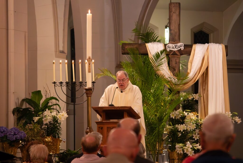 Father speaks in front of a large cross at St. Patrick's in Youngstown. Photo by Courtney Poullas.