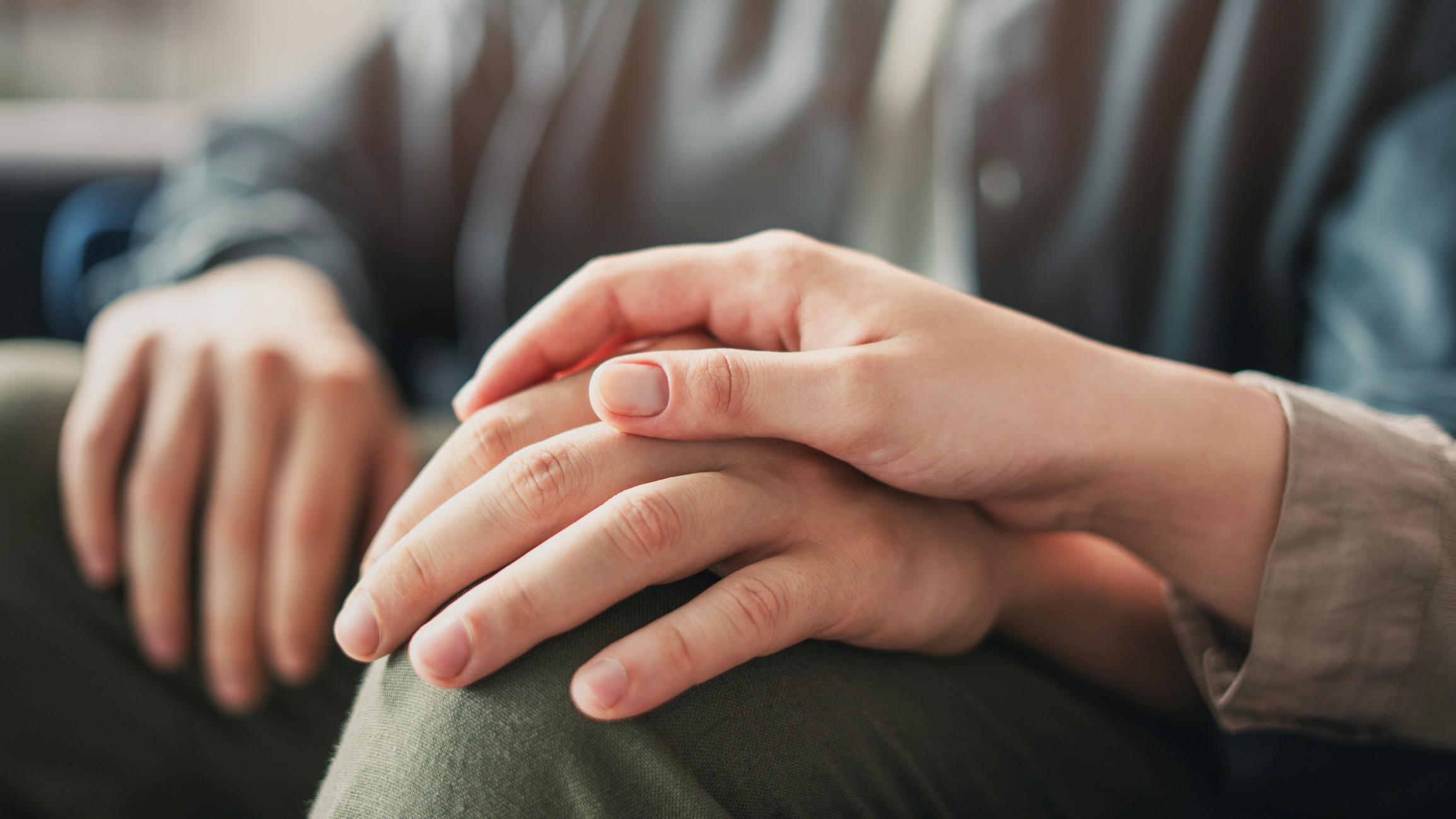 A woman comforts someone with her friendship by placing her hand over his.