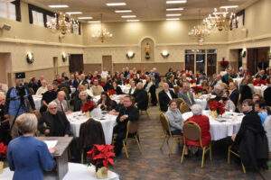 159 guests sit at tables decorated with Poinsettias, in Our Lady of Mt. Carmel Hall, Youngstown.