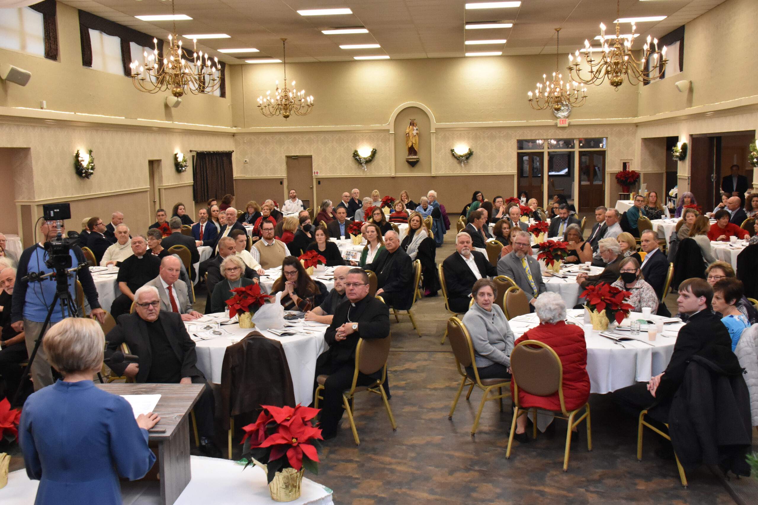 159 guests sit at tables decorated with Poinsettias, in Our Lady of Mt. Carmel Hall, Youngstown.