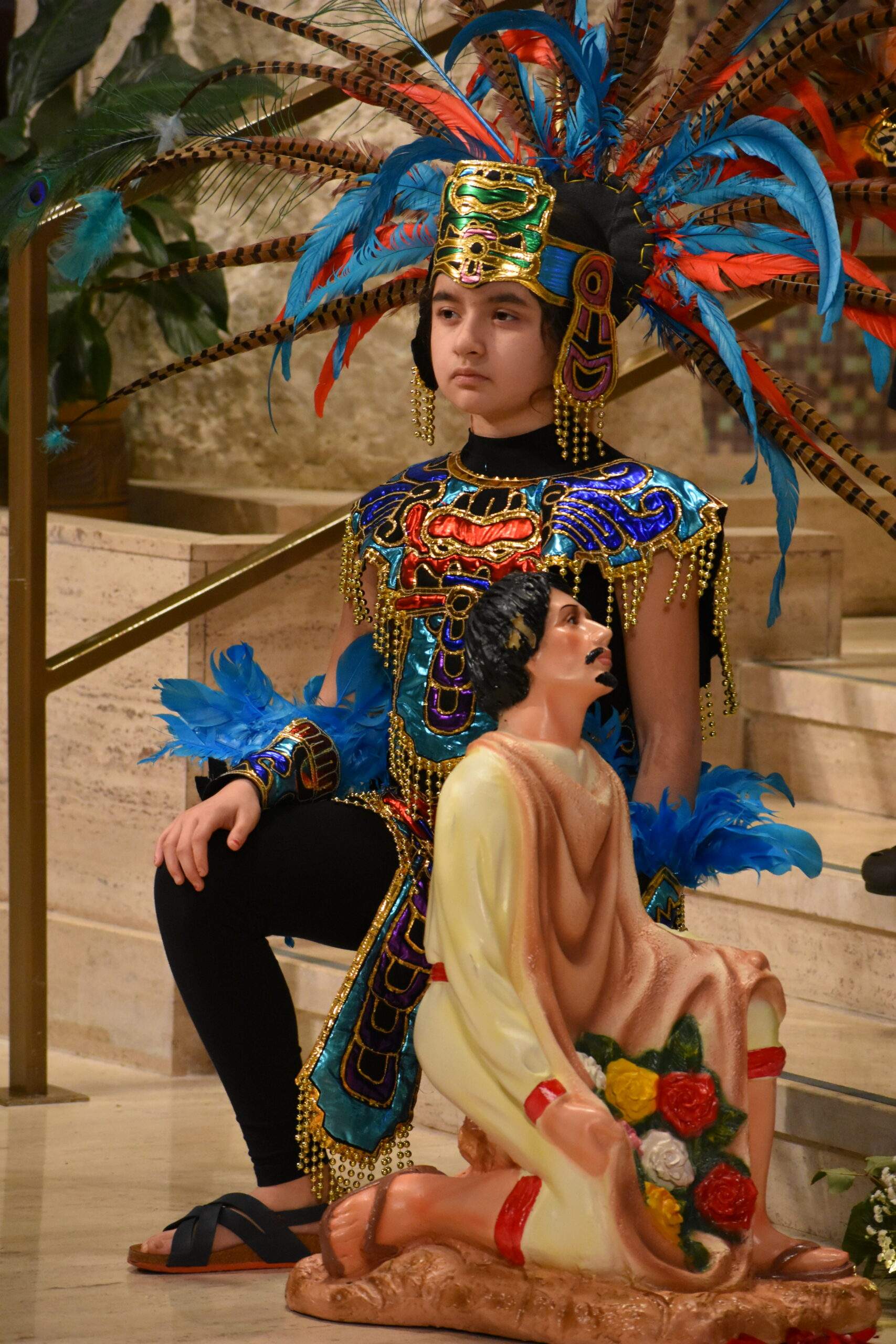 A young boy wearing a headdress participates in the Our Lady of Guadalupe reception performances.