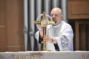 Priest places the monstrance on the altar at St. Christine Parish