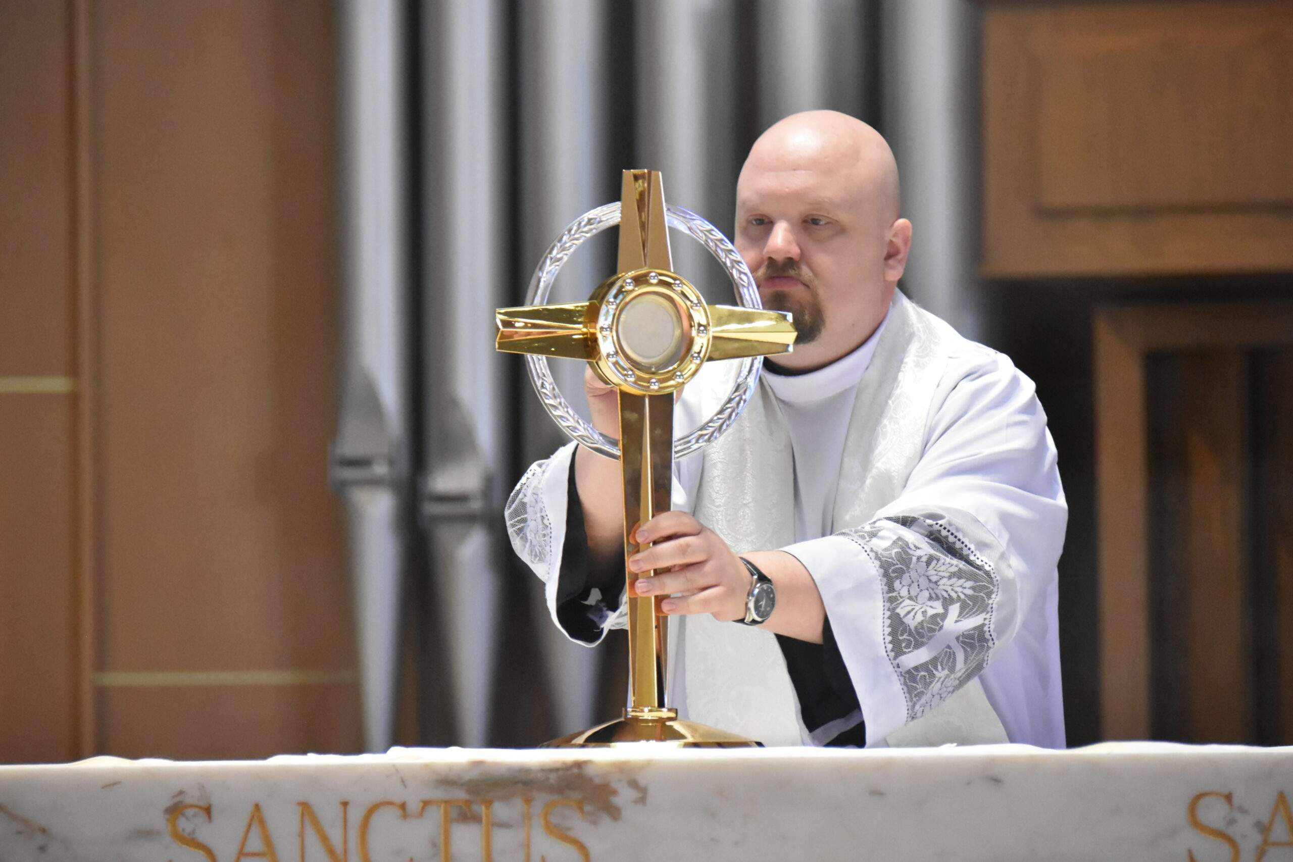 Priest places the monstrance on the altar at St. Christine Parish