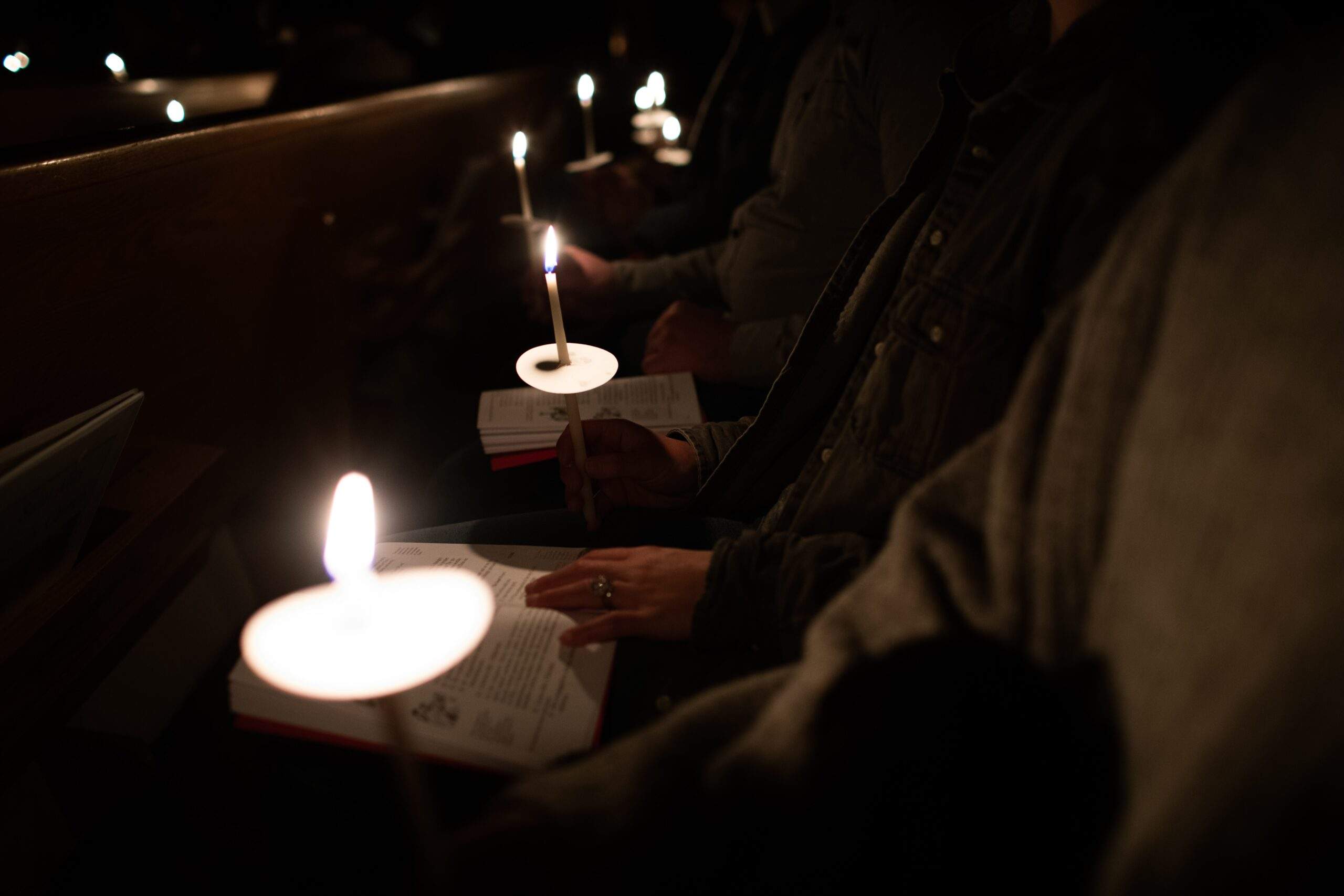 people sitting in a church with lit candles