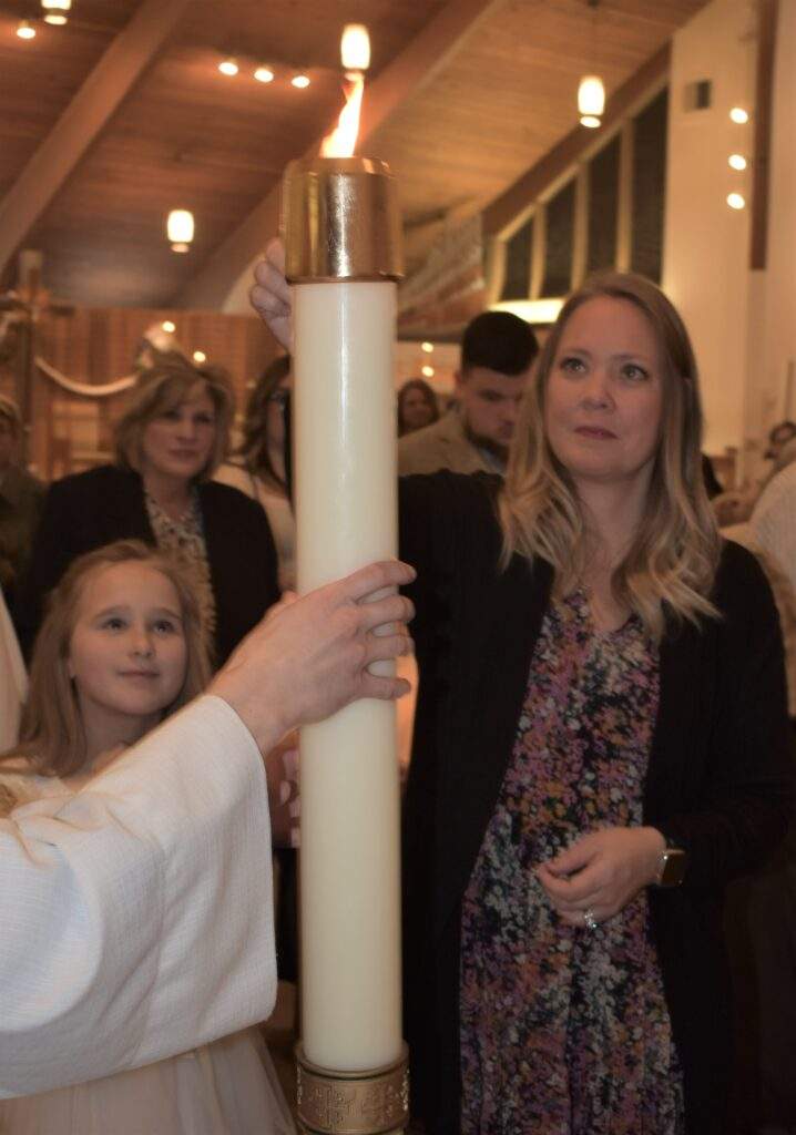 Mother and daughter light a candle at the Easter Vigil