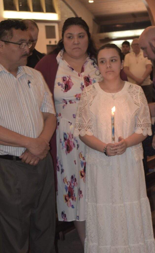 Parents stand with their daughter, who holds a candle, at the Easter Vigil