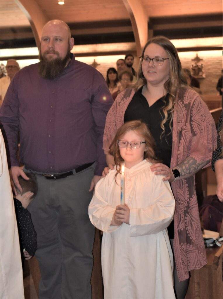 Parents stand with their daughter, who holds a candle, at the Easter Vigil