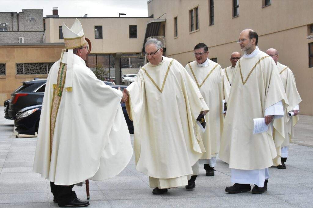Bishop Bonnar greets his brother priests outside St. Columba Cathedral before the Chrism Mass.
