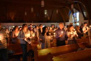 Parishioners hold candles during the beginning of Mass at the Easter Vigil in Columbiana