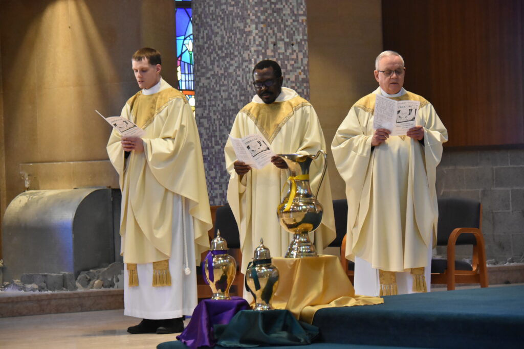 Three priests stand with jugs of water at the Holy Thursday Mass at St. Columba Cathedral