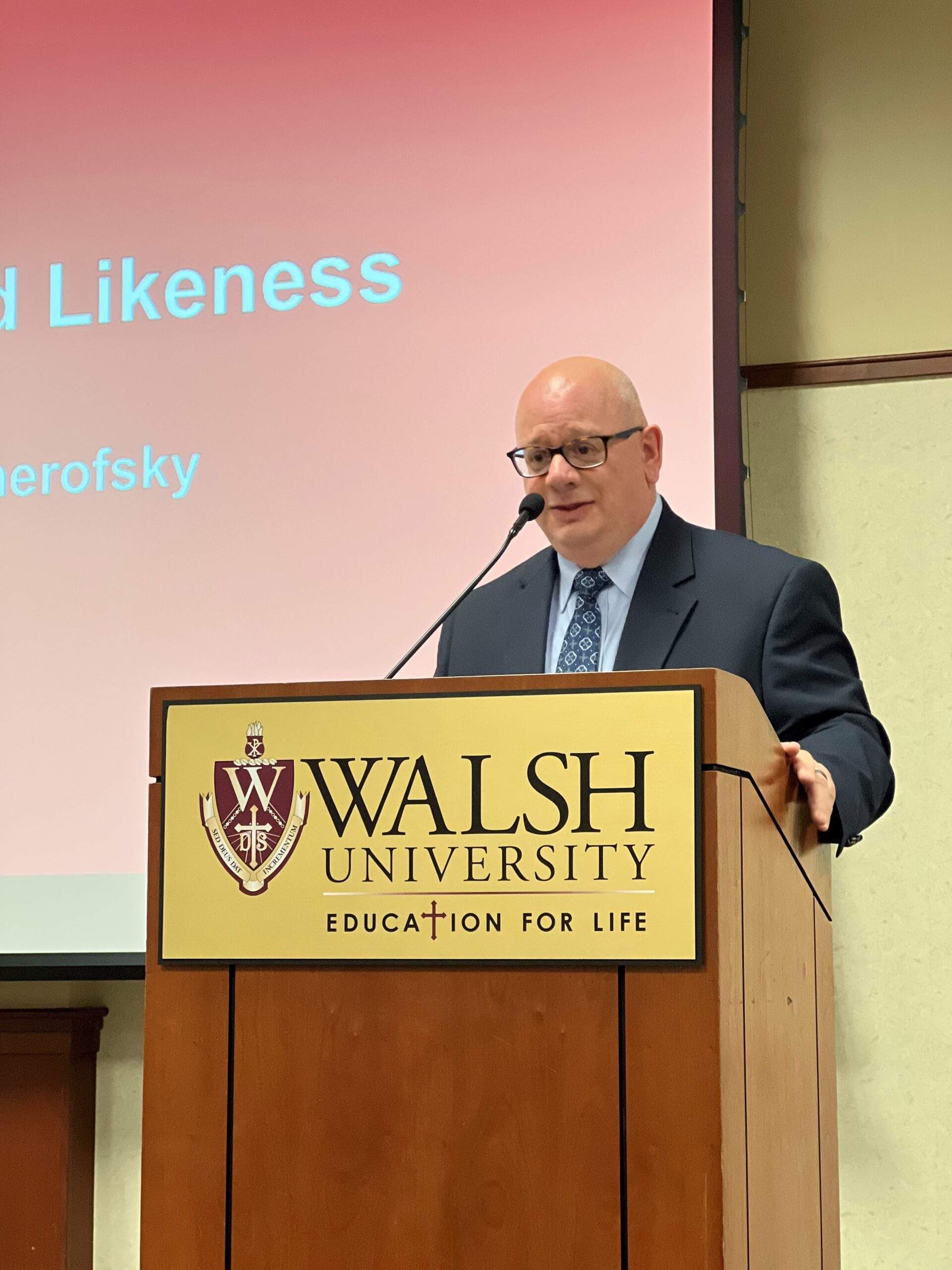 Presenter stands at a podium during Walsh's Education for Life series.