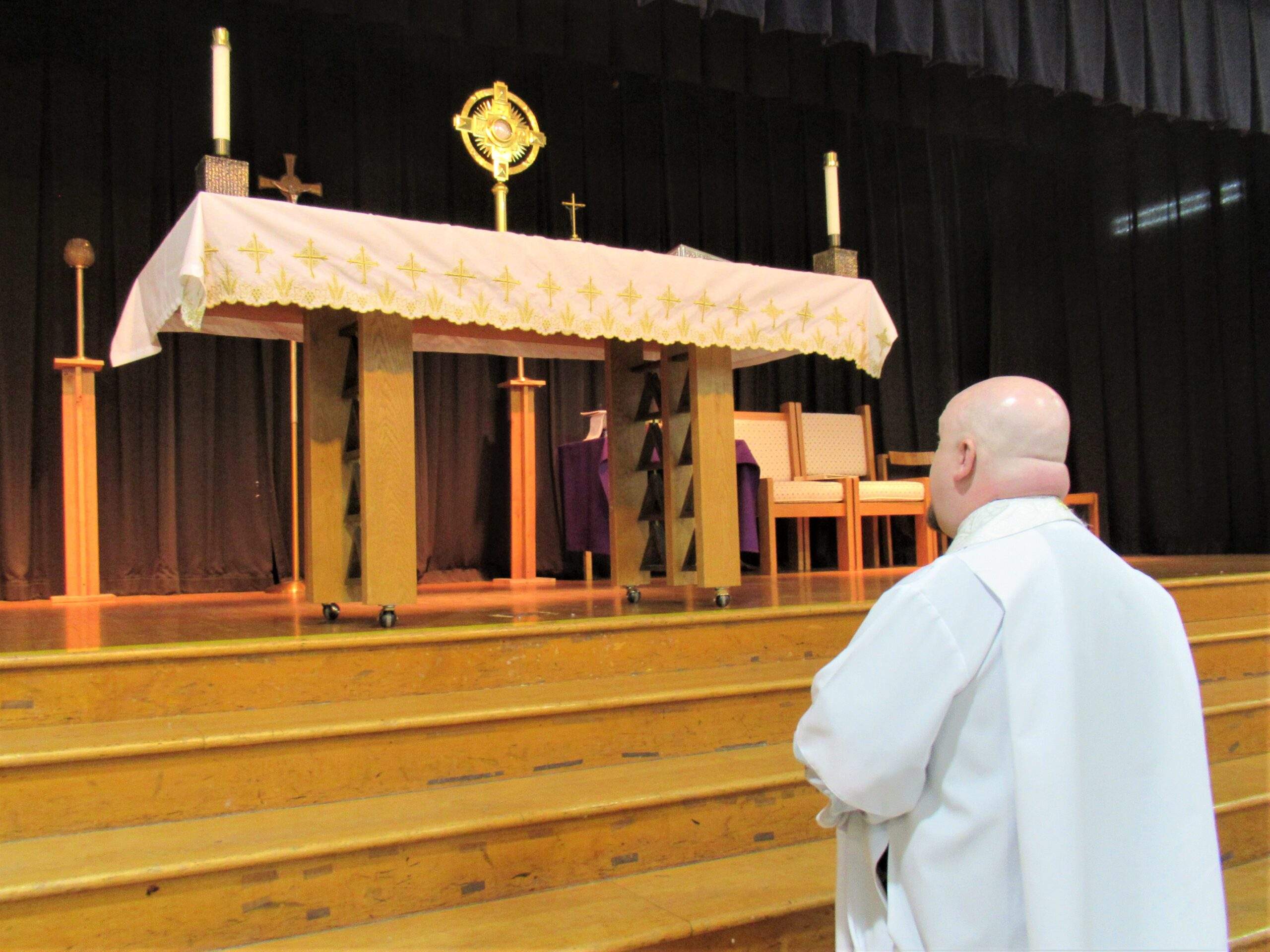 Father Ryan Furlong prays before the monstrance with the Blessed Sacrament on the altar during adoration at the Youngstown Catholic Men's Fellowship Conference March 25 at Warren John F. Kennedy High School.