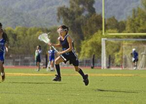 A young girl plays lacrosse.