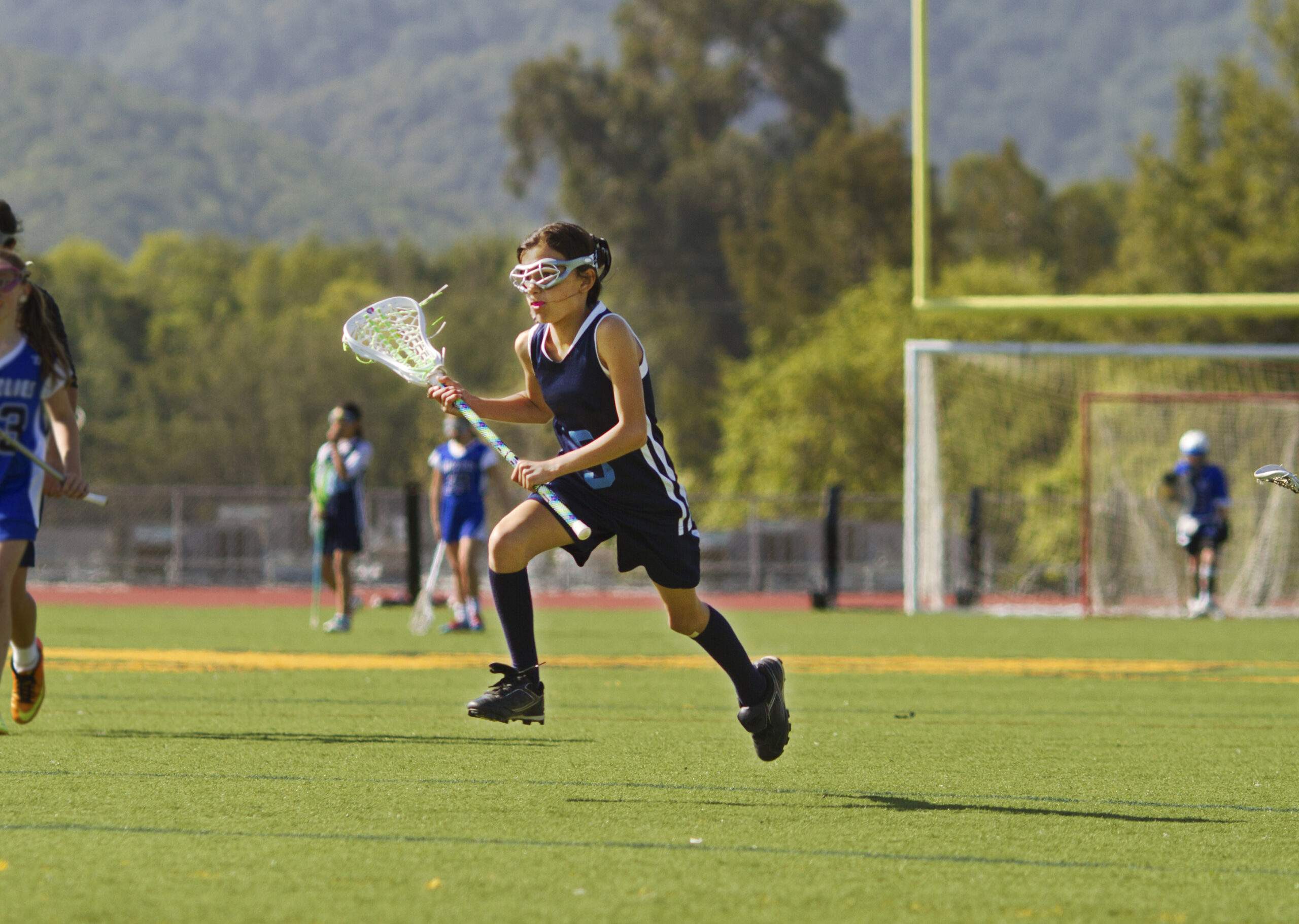 A young girl plays lacrosse.