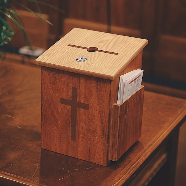 A wooden tithe box with a cross on the front.