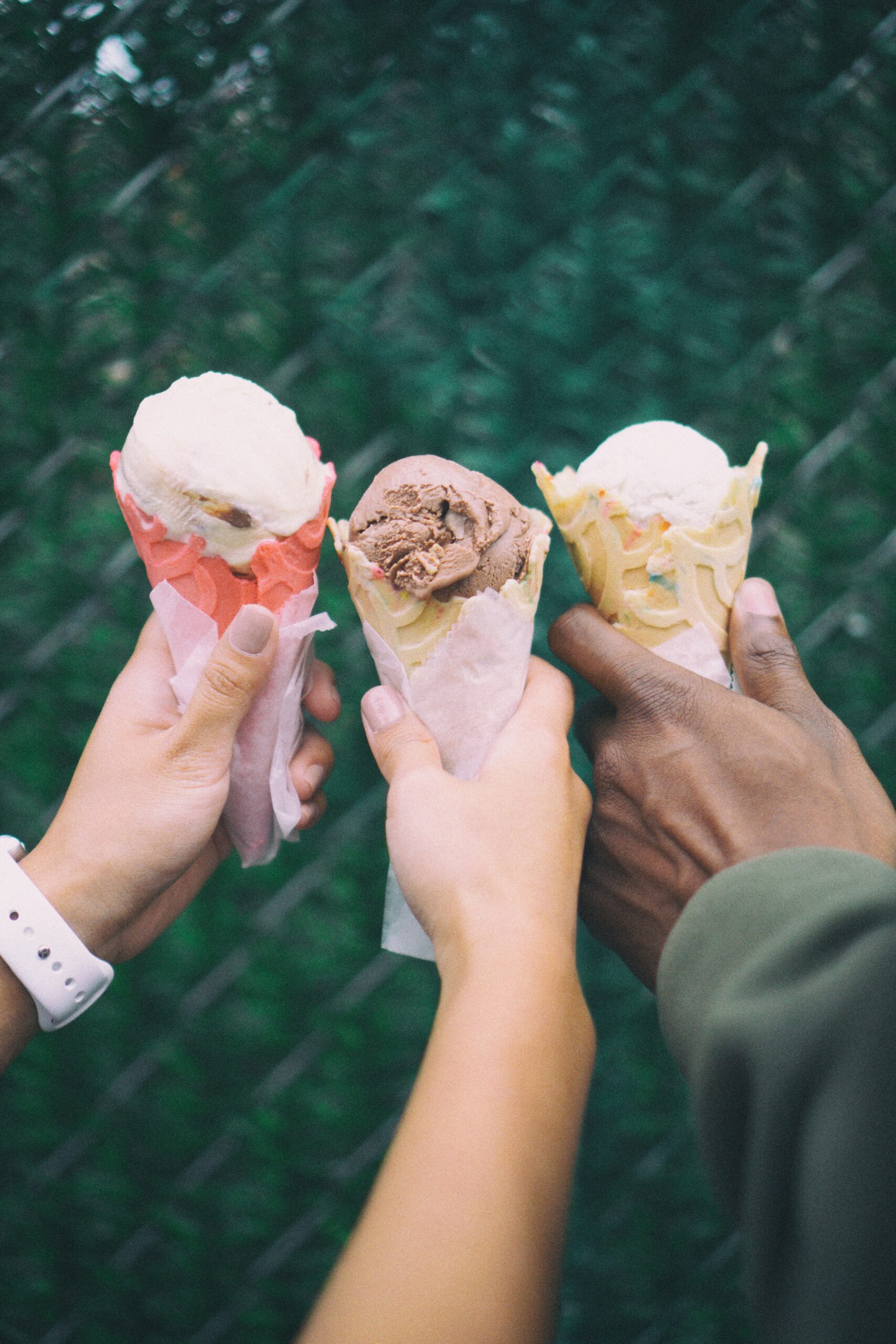 three hands holding three ice cream cones