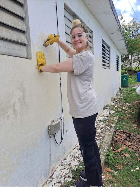 Student scrapes paint on the side of a house.