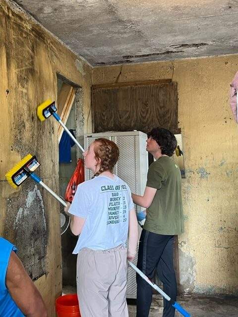 Two students mop walls that were damaged