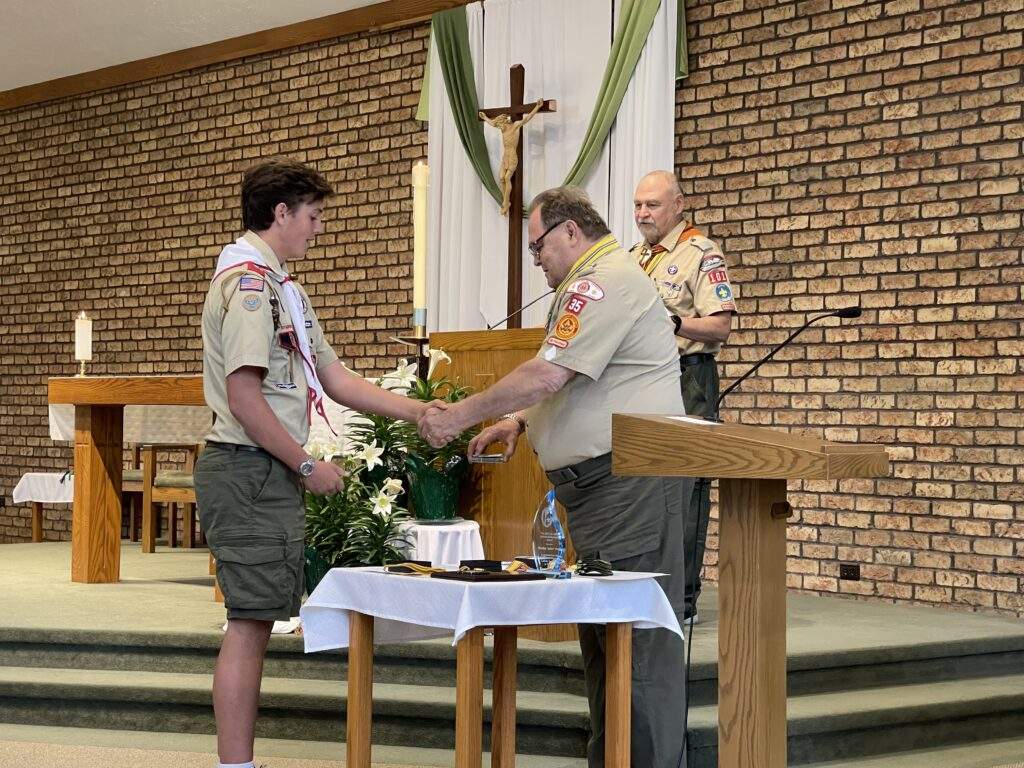 Davis shakes hands with the deacon, while receiving his scouting award.