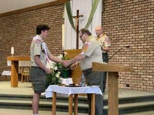 Davis shakes hands with the deacon, while receiving his scouting award.