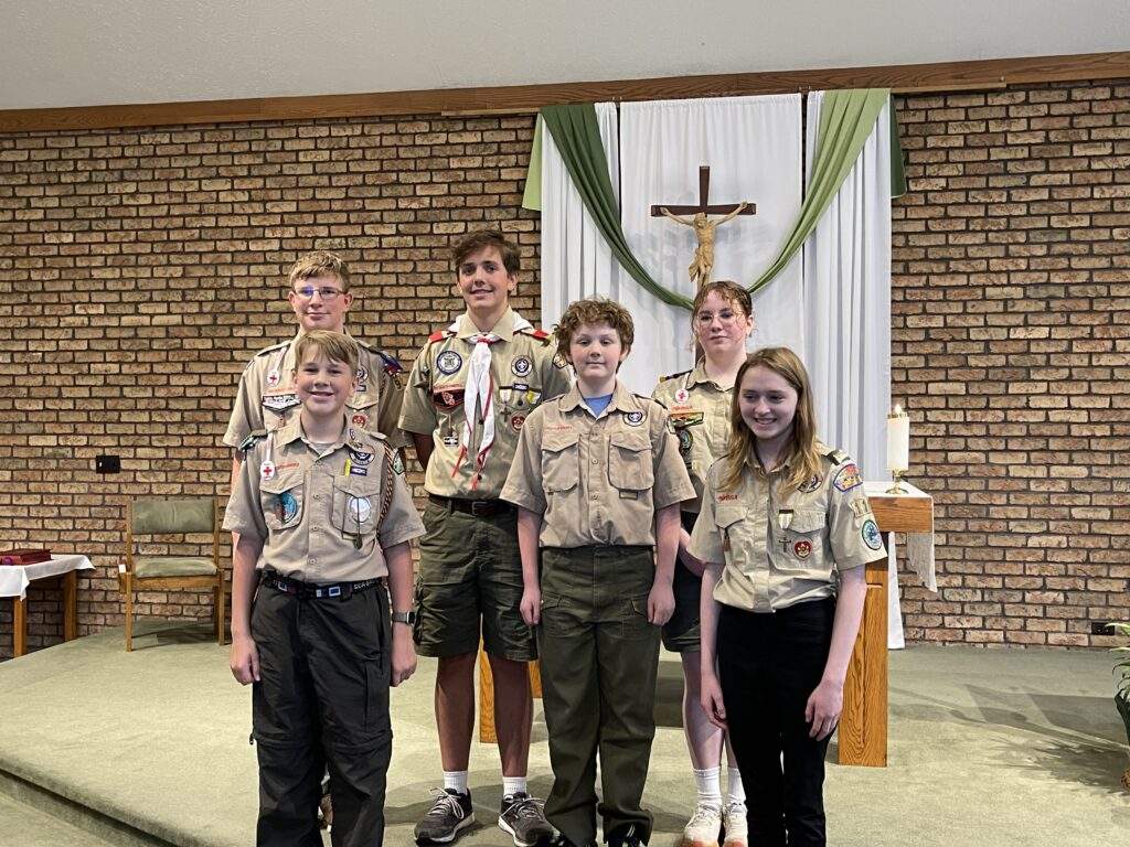 The six awardees, dressed in scouting clothes, stand near the altar
