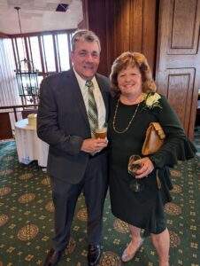An award recipient in a green dress, poses with man in gray suit.