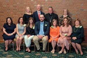 The award recipients, seated, stand with Bishop Bonnar and other Catholic School leaders in the diocese.