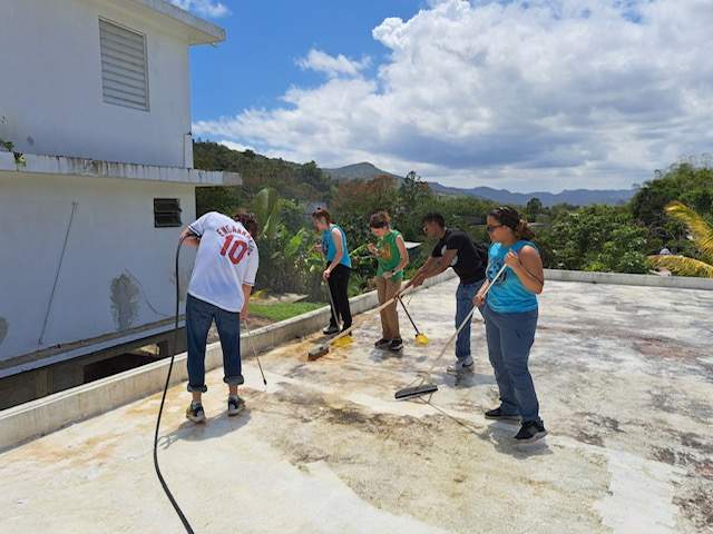 A group of four students mop the roof of a building