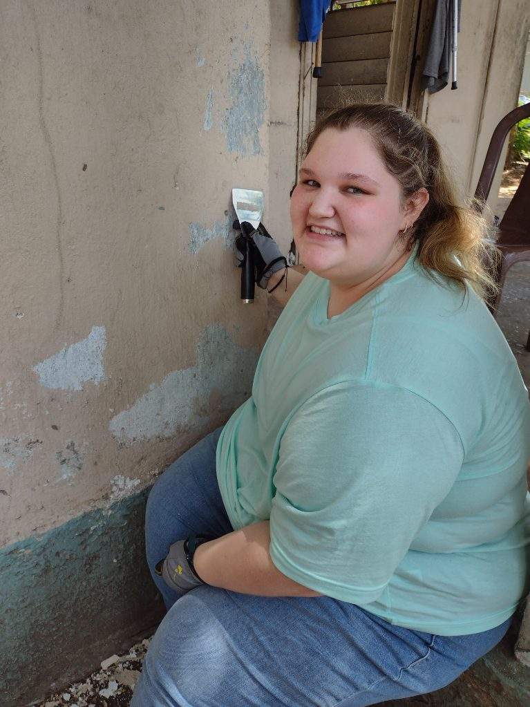 Student scrapes paint on a beige-colored house.