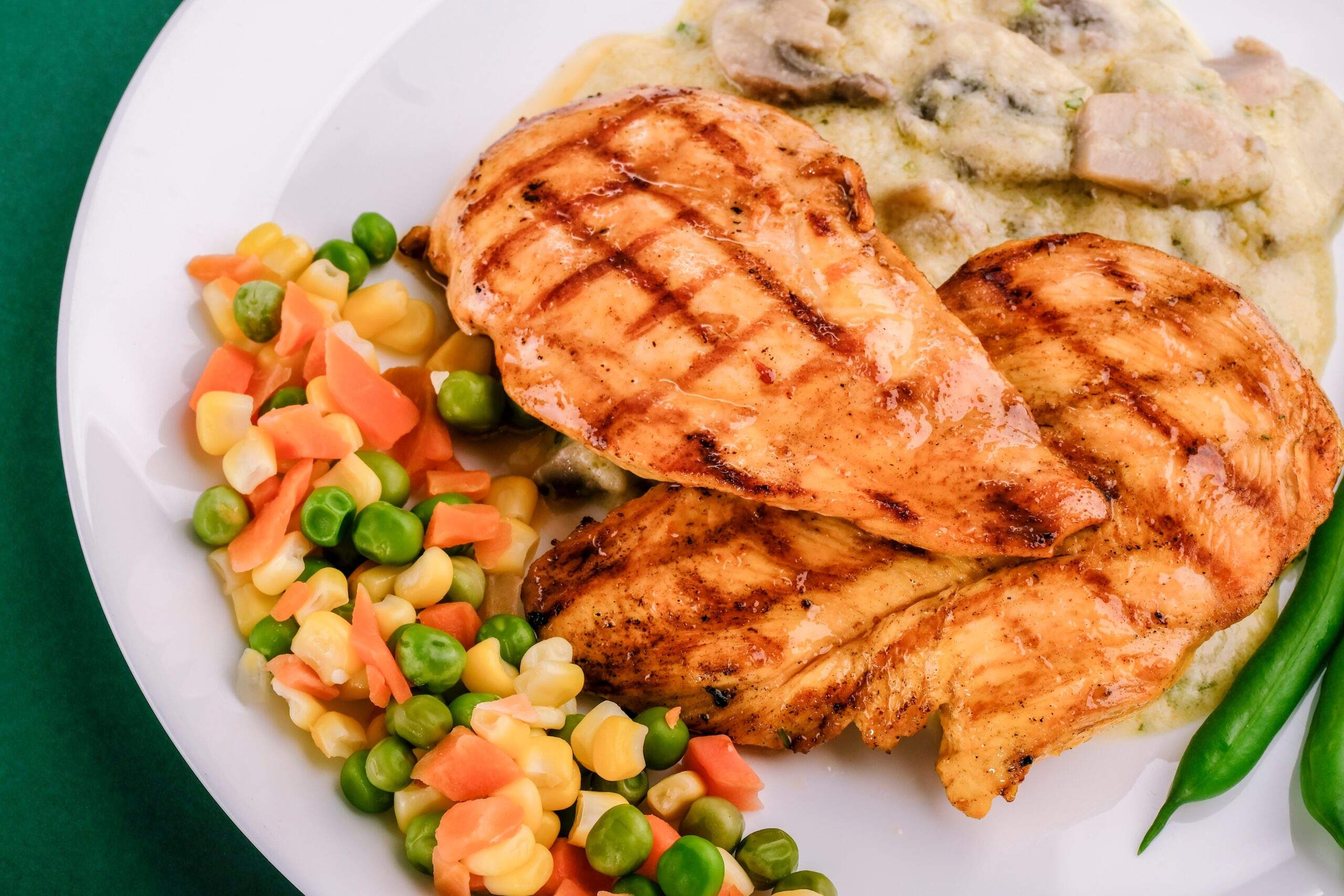 Chicken dinner and vegetables on white plate