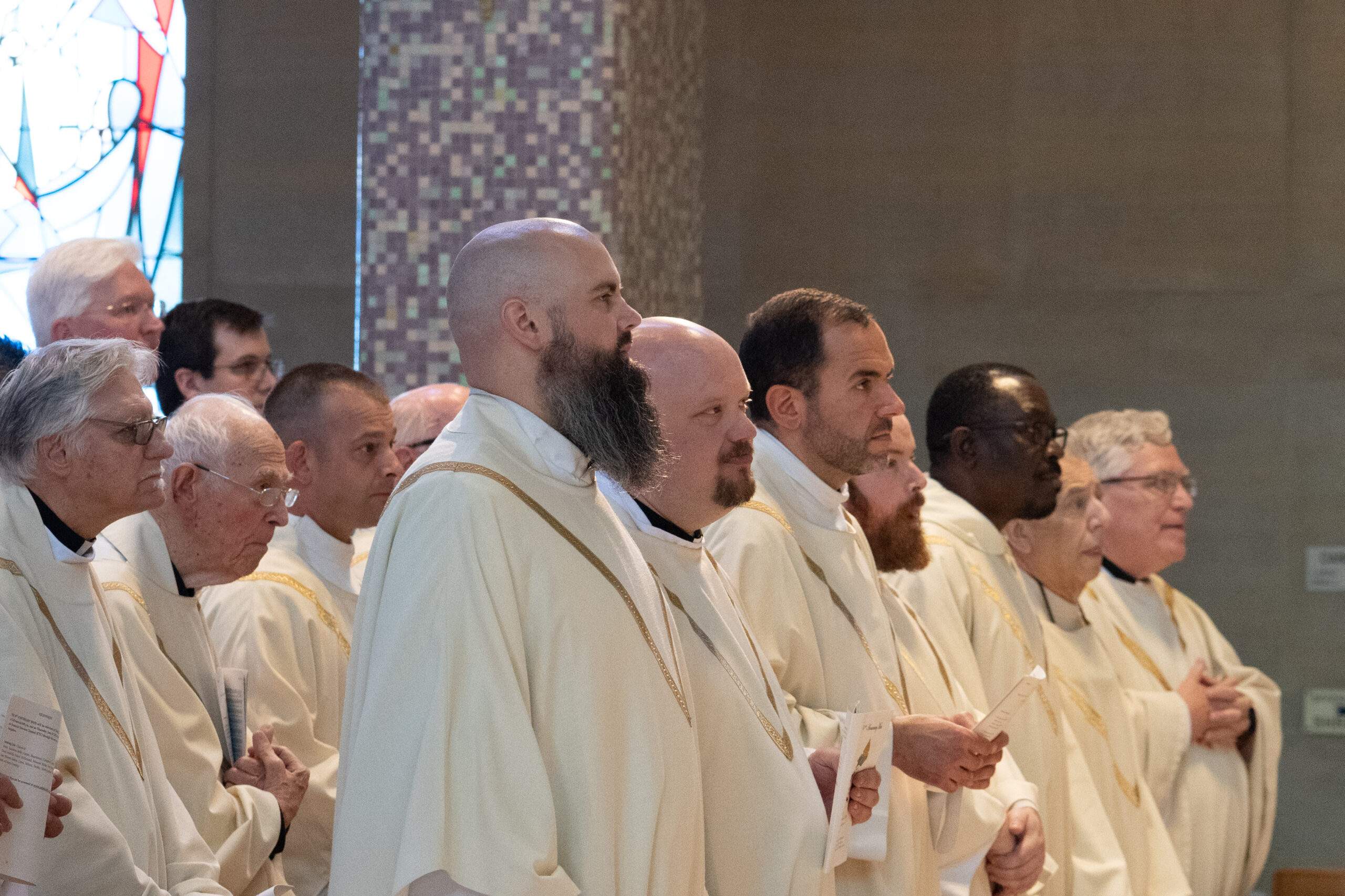 Priests stand during Mass