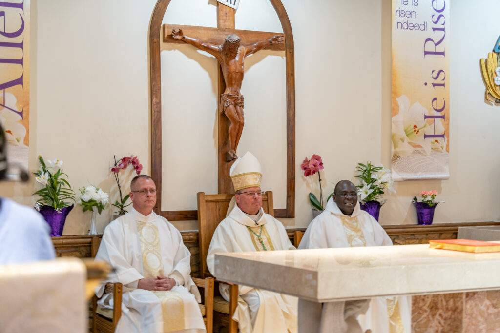 Bishop Bonnar, priest and deacon seated behind the altar at Sacred Heart Parish in Rock Creek. Photo by Brian Keith